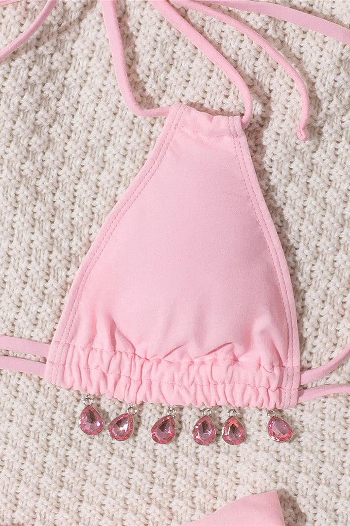 Pink bikini top with gemstone details on a textured surface