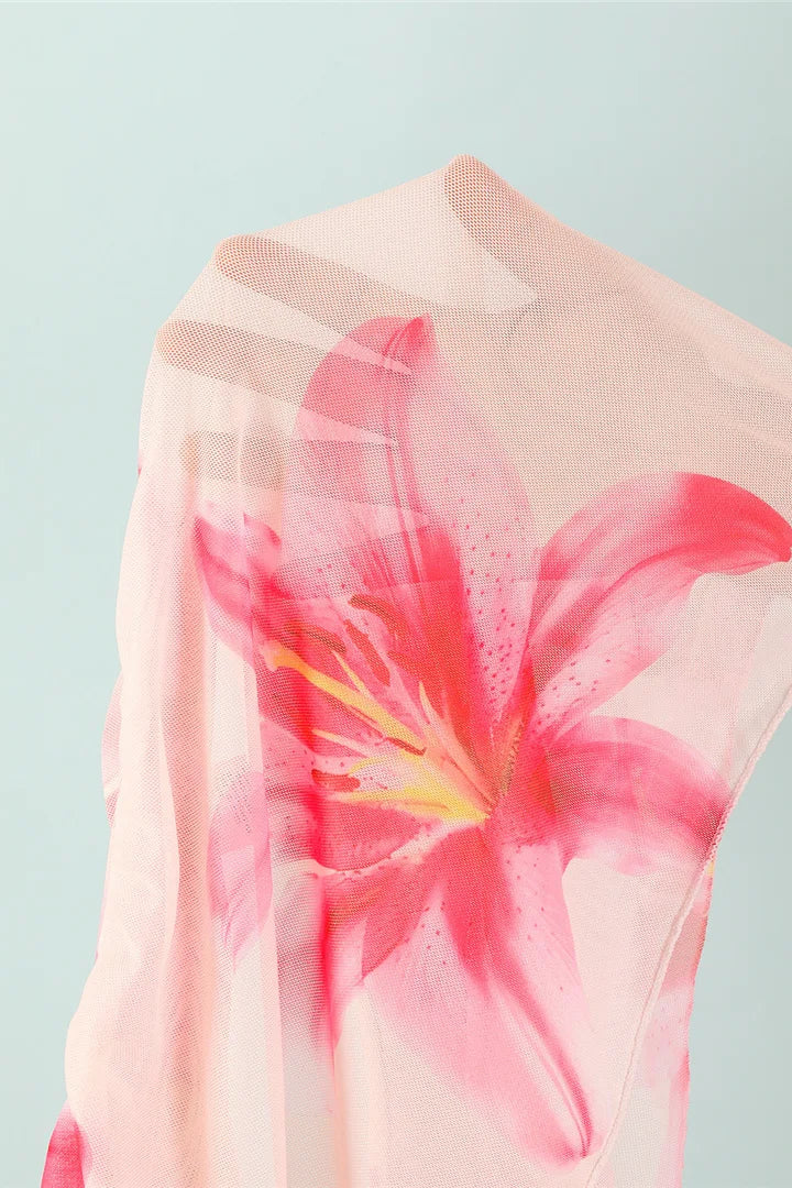 Pink floral sheer cover up skirt held by a person against a light blue background