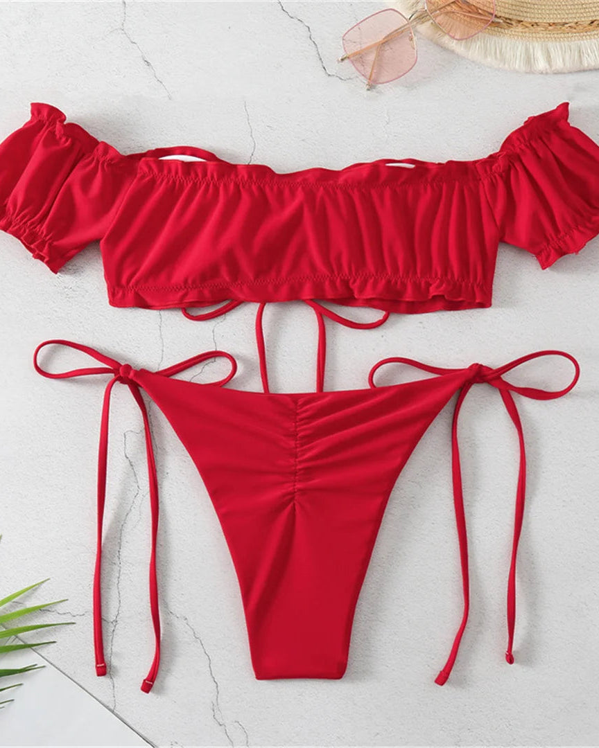 Red bikini set with ruffled bikini top and bottom and tied sides on a light gray background.