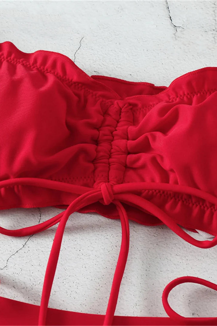 Red bikini top with straps on a light gray surface