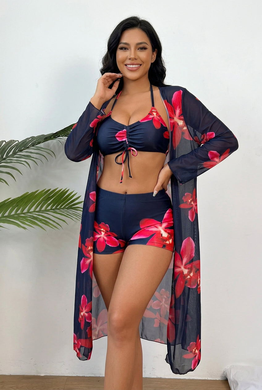 Stylish three-piece beachwear set featuring a black base with pink floral print, a halter bikini top, matching shorts, and a long-sleeve cover-up.
