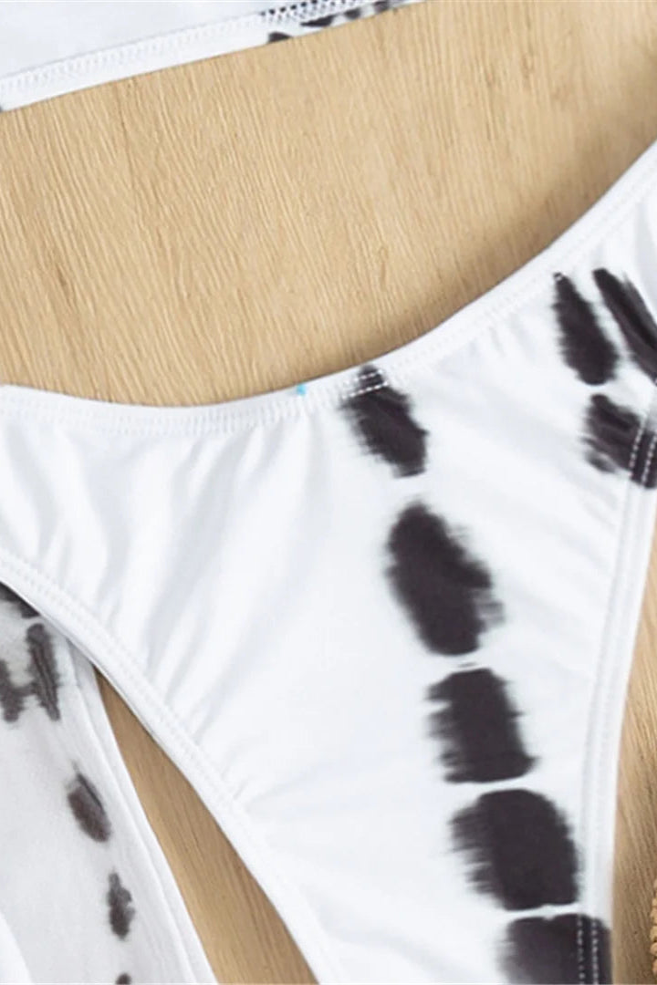 White bikini bottom with black tie-dye pattern on a wooden surface