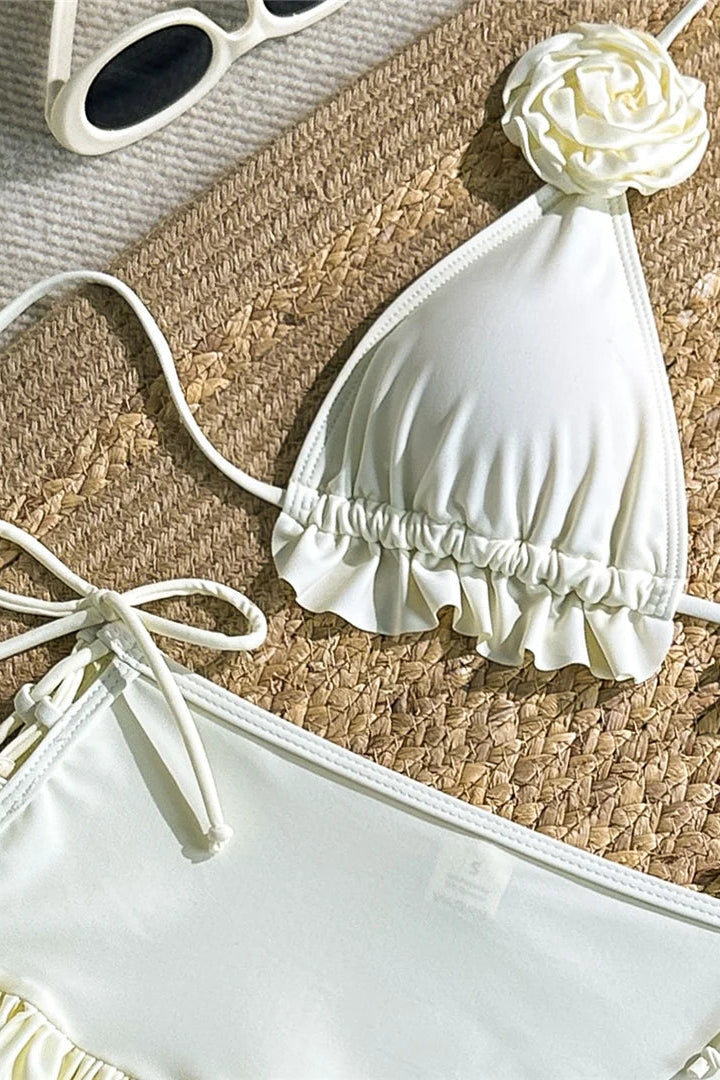 White bikini set with floral details on a woven mat