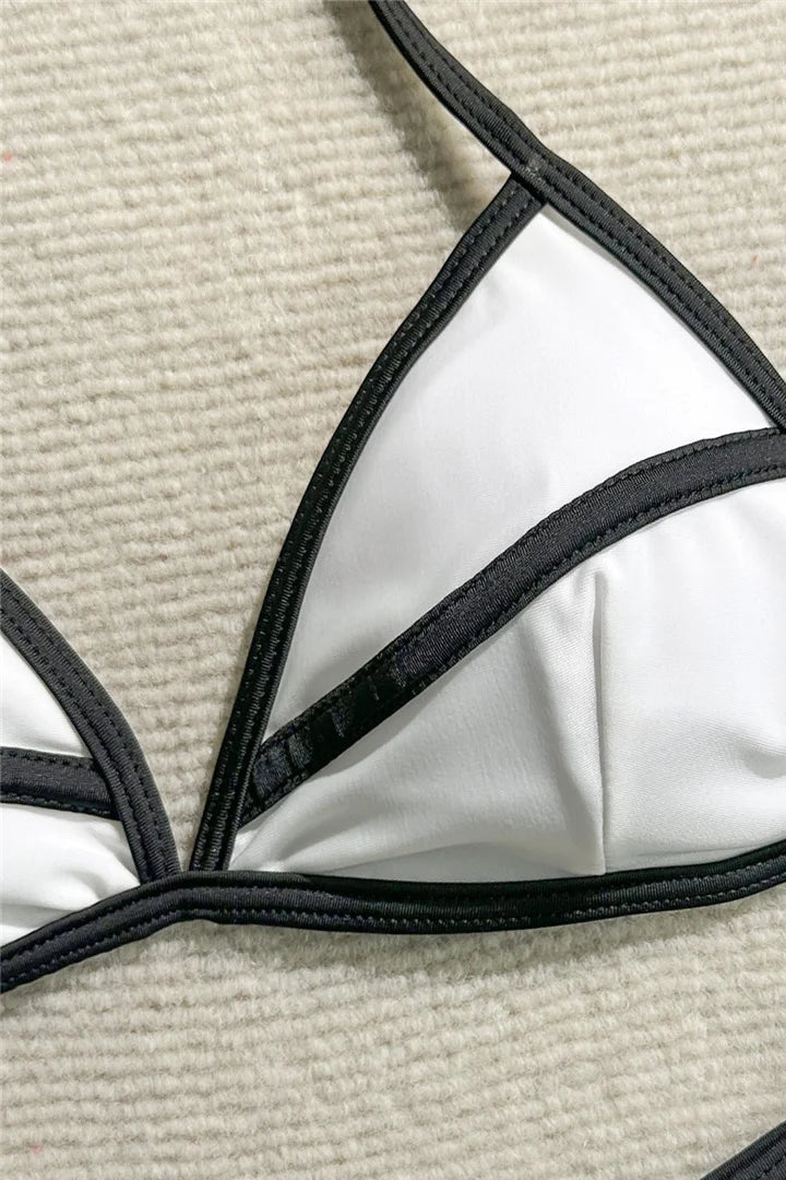 White bikini top with black straps on a beige surface