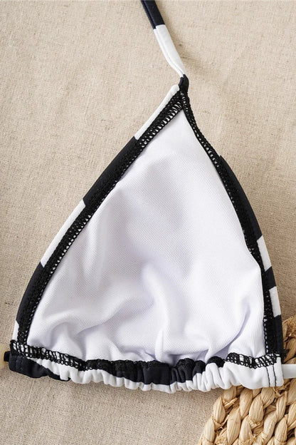 White bikini top with black trim on a beige fabric background