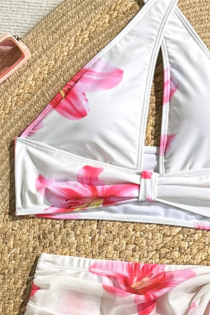 White bikini top with pink floral pattern on a woven surface