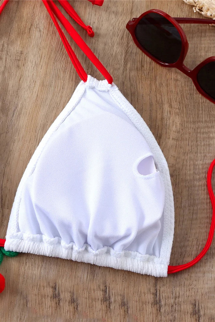White bikini top with red straps on a wooden surface
