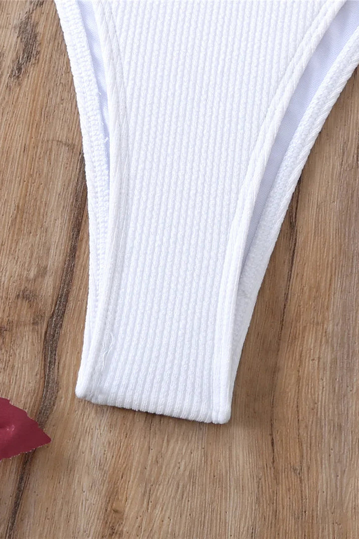 White ribbed underwear on a wooden surface with a red flower.