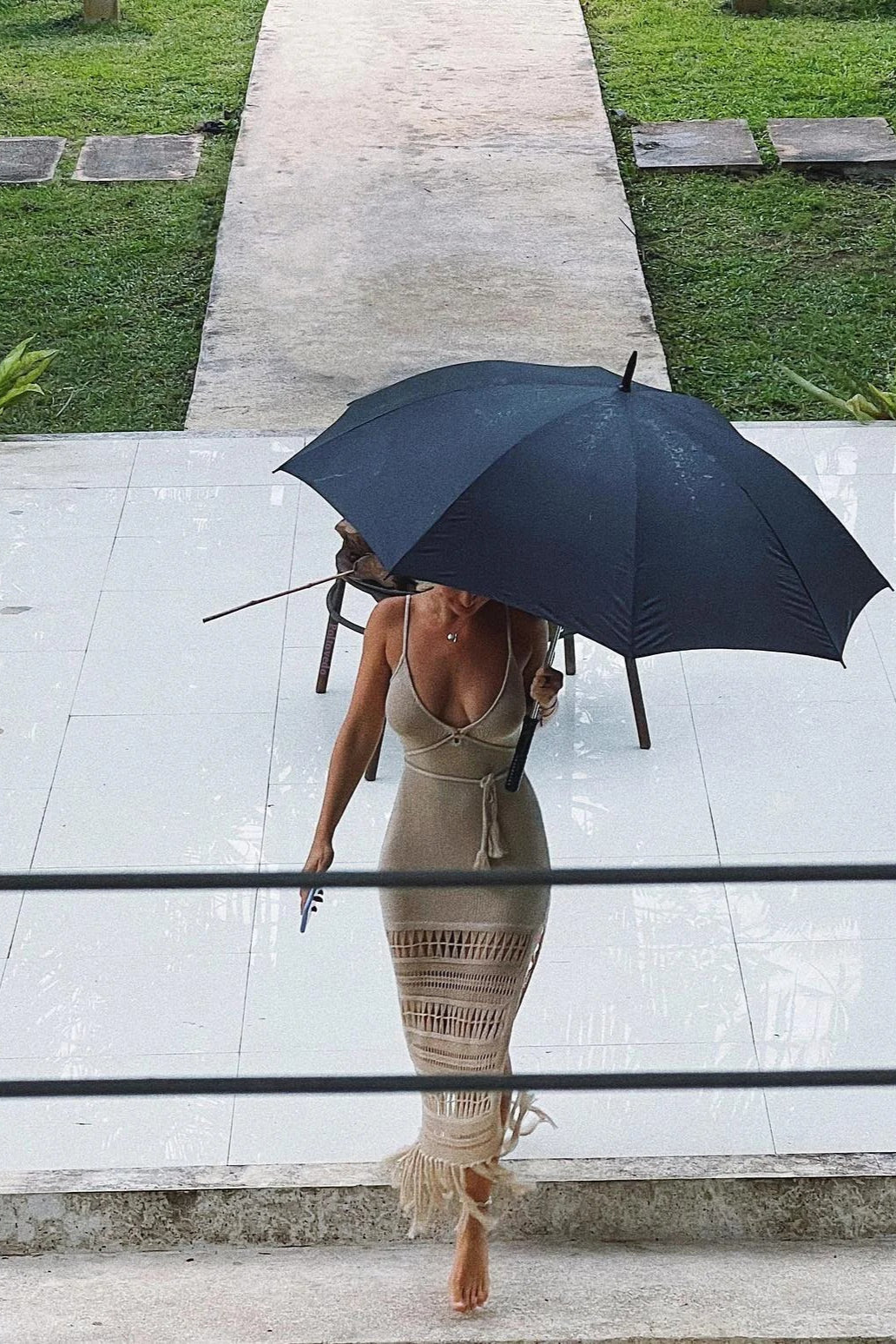 Woman holding a black umbrella wearing cover up fringe maxi dress