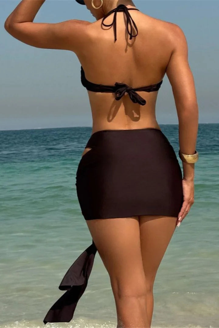 Woman in a brown bikini standing on a beach with clear blue water dcostaa swimwear