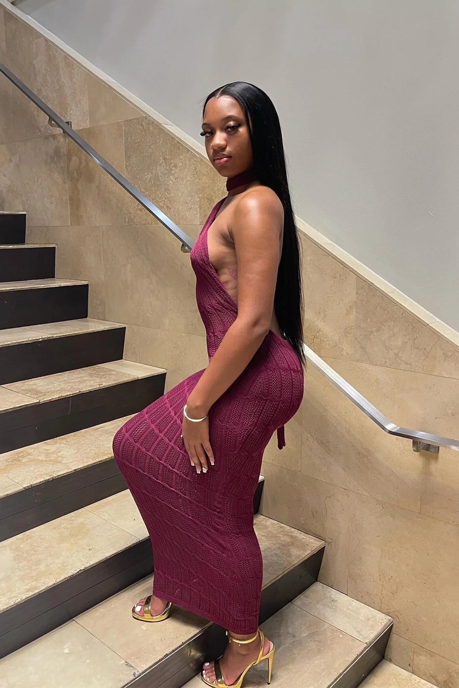 Woman in a burgundy dress standing on a staircase