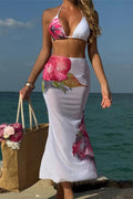 Woman in a floral bikini and skirt standing by the ocean