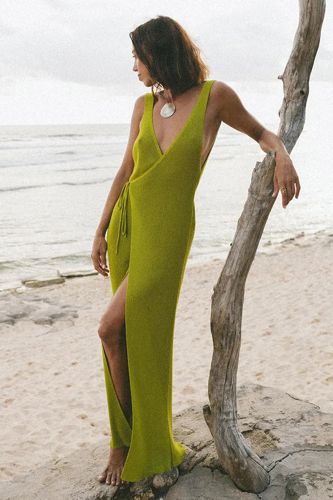 Woman in a green cover up standing by a tree on a beach