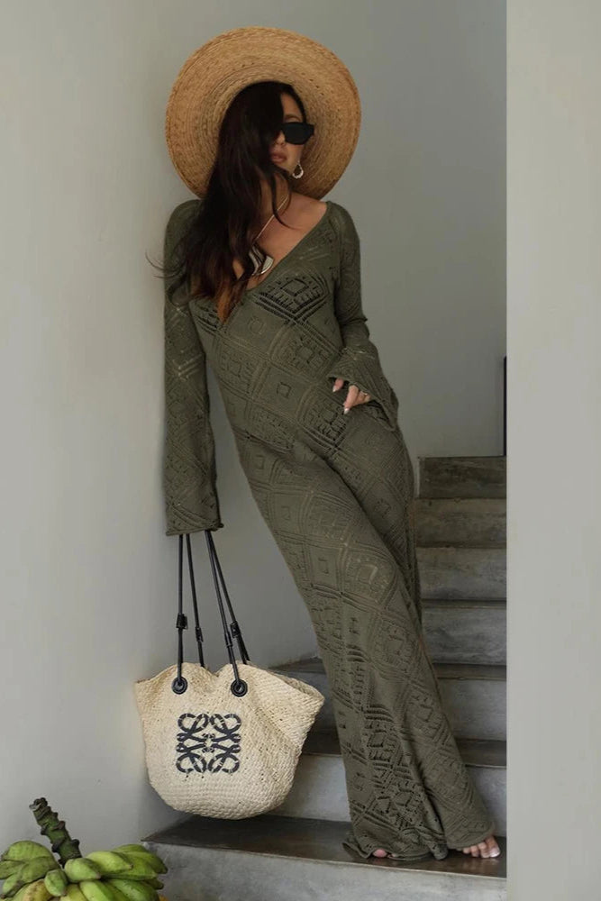 Woman in a green outfit with a straw hat and sunglasses, standing on steps.