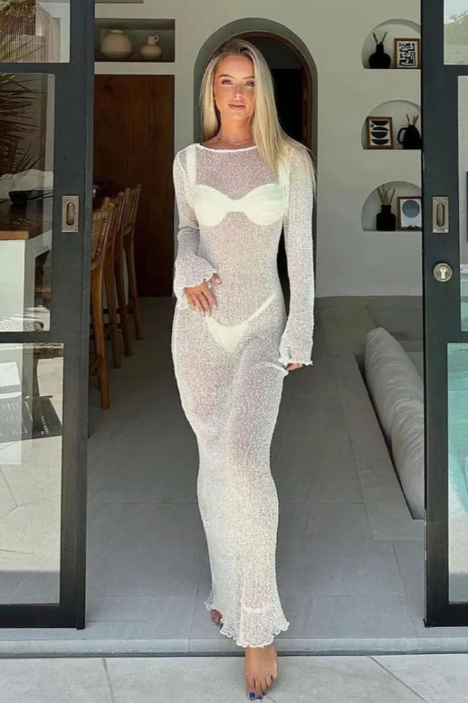 Woman in a sheer white cover up standing in a modern home interior.