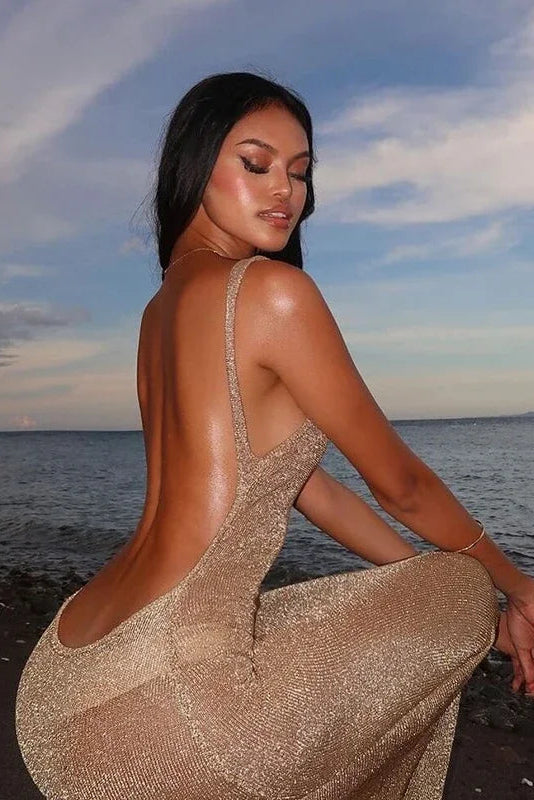 Woman in a sparkly dress sitting by the water with a scenic background