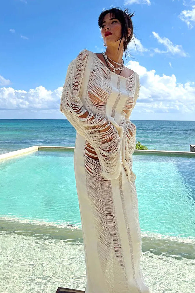 Woman in a white beach cover up dress standing by a pool with ocean view