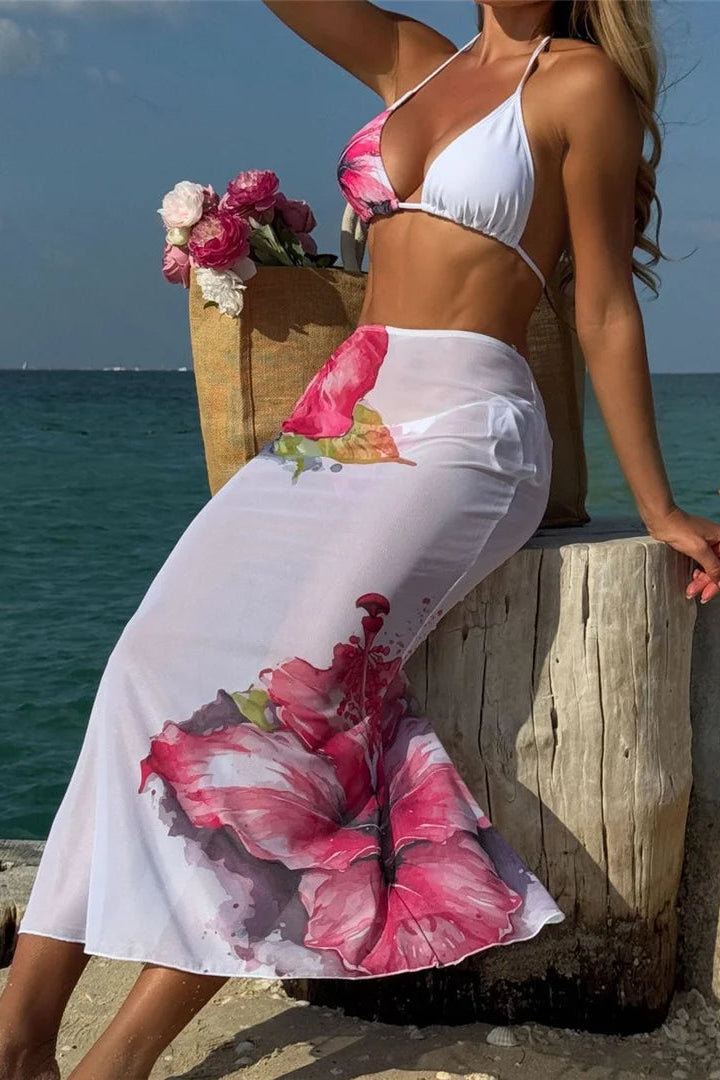 Woman in a white bikini and floral skirt by the ocean