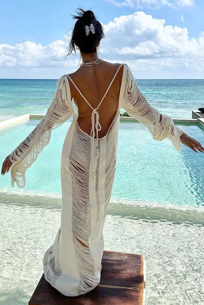 Woman in a white cover up with a open back beach wear standing by a pool with ocean view