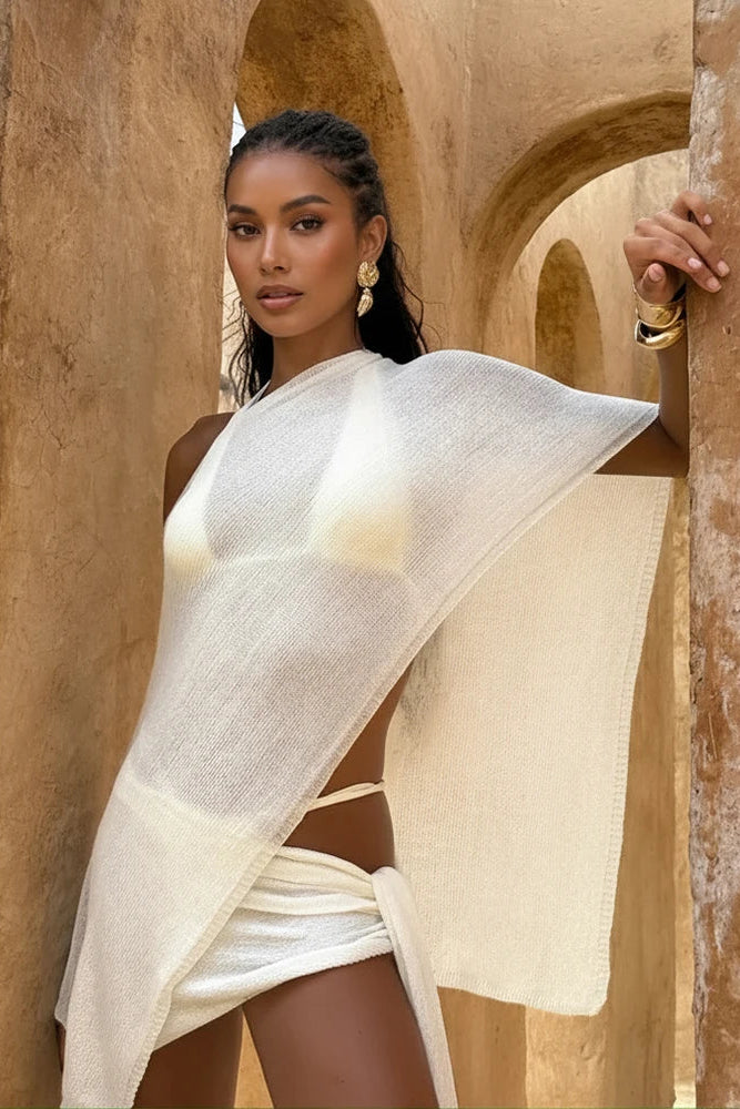 Woman in a white dress standing in front of a stone archway