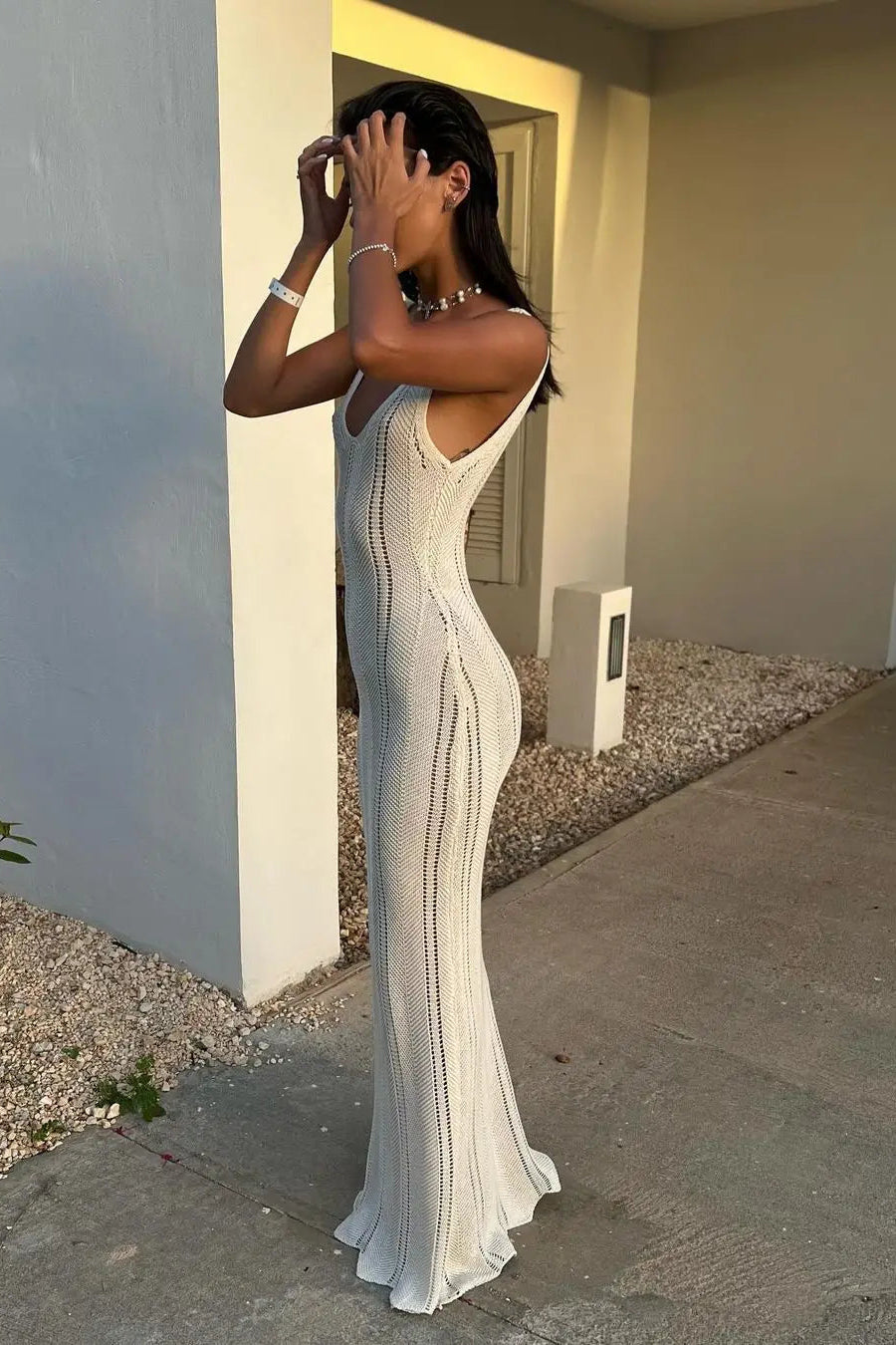 Woman in a white dress standing outdoors near a building.