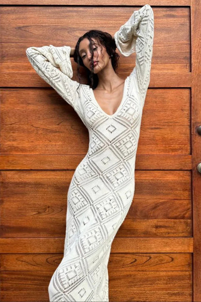 Woman in a white patterned dress standing against a wooden door