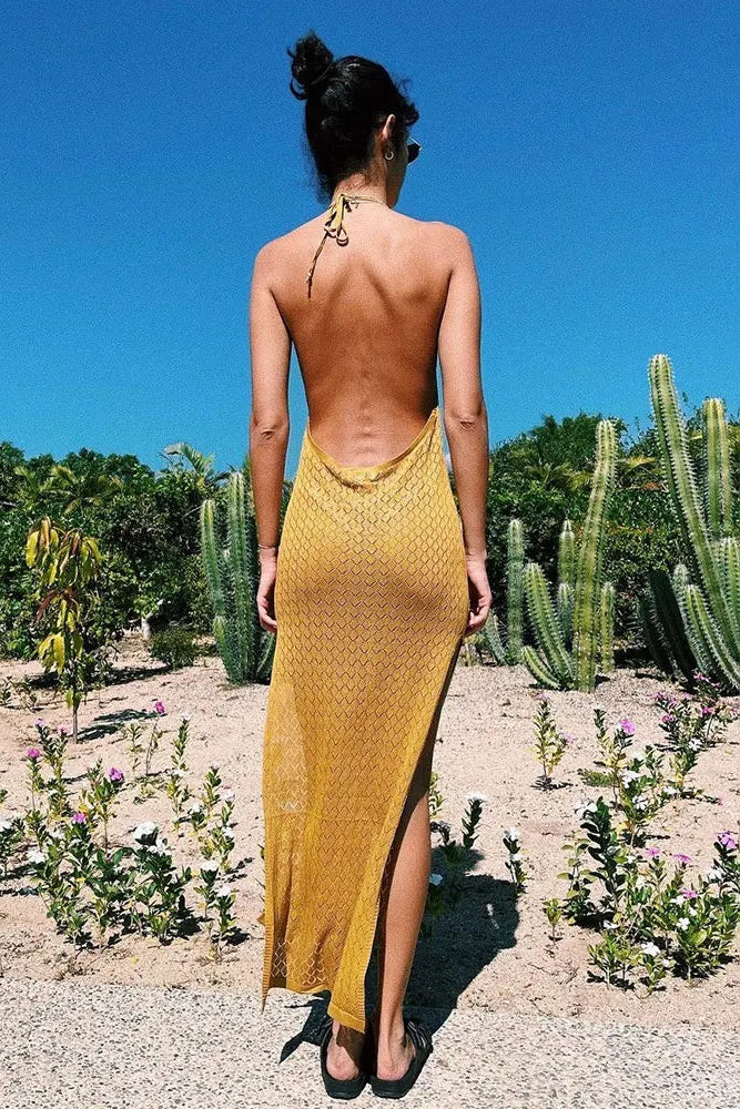 Woman in a yellow dress standing in a desert landscape with cacti and flowers.