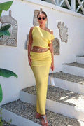Woman in a yellow dress standing on a white wall with decorative elements