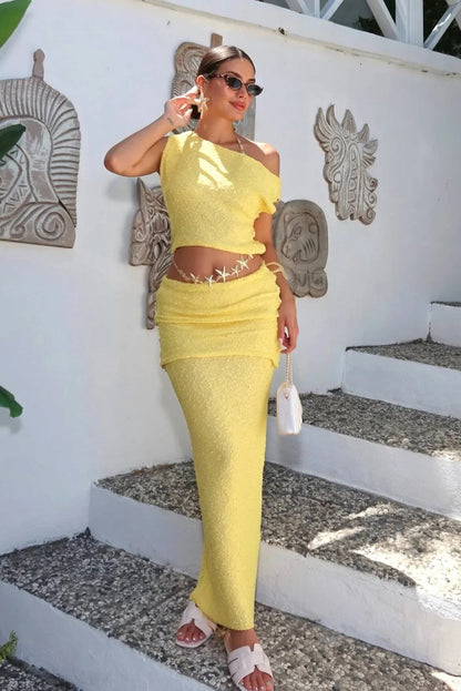 Woman in a yellow outfit standing on steps with decorative wall art in the background