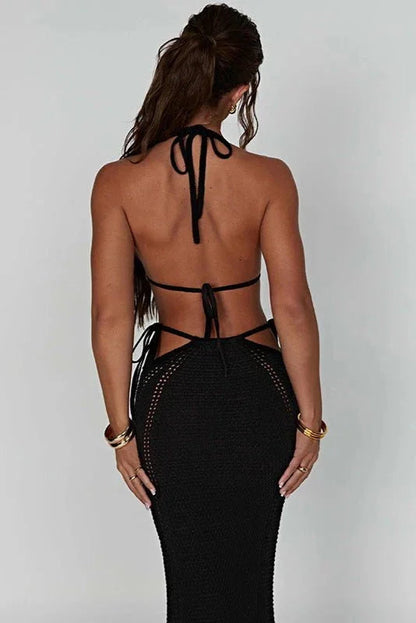 Woman wearing a black 2 piece set with cut-out back design on a plain background