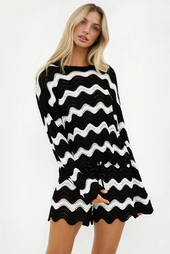 Woman wearing a black and white striped cover up top and shorts on a white background