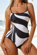 Woman wearing a black and white striped monokini swimsuit on a beach.