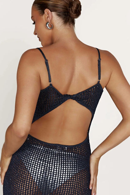 Woman wearing a black cover up dress with an open back on a white background