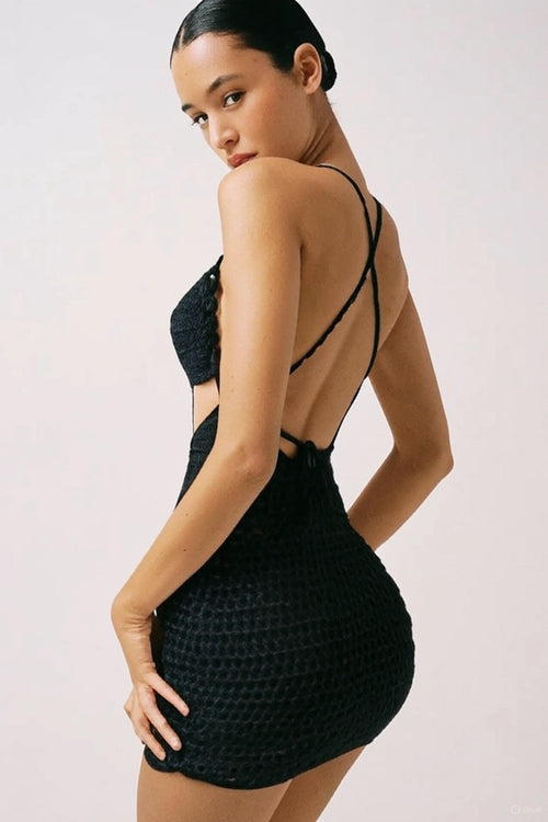 Woman wearing a black textured dress with thin straps on a light background