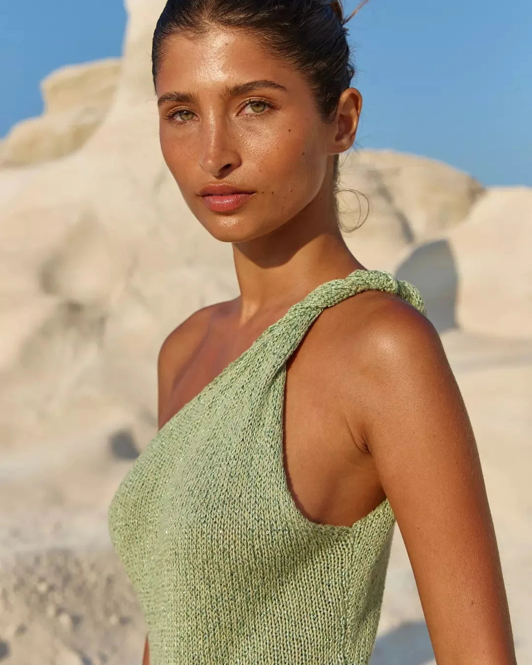 Woman wearing a green knitted cover up against a desert background