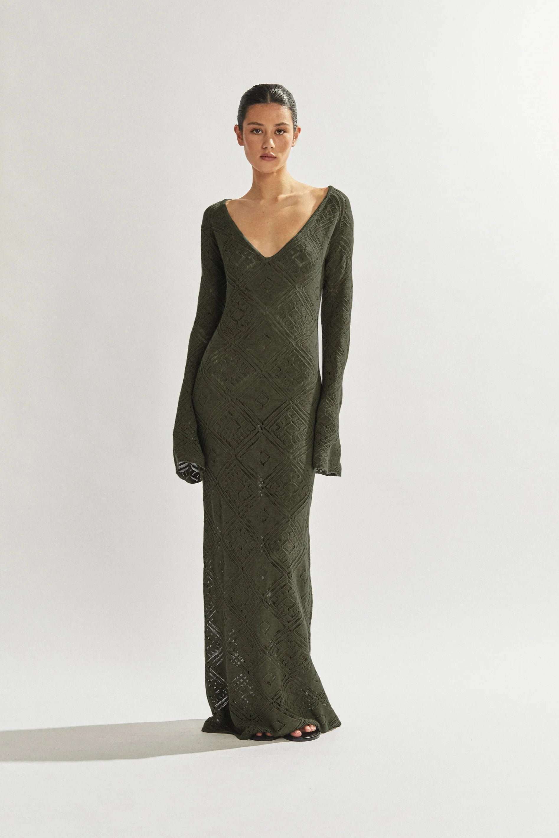 Woman wearing a green long-sleeve dress against a white background