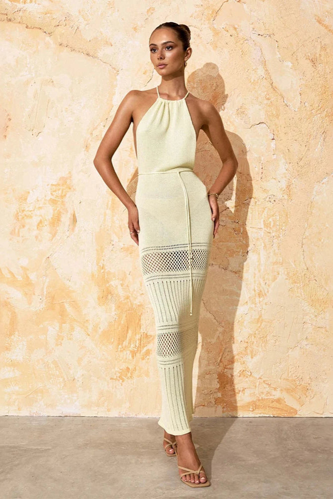 Woman wearing a light cream cover up dress against a textured beige wall