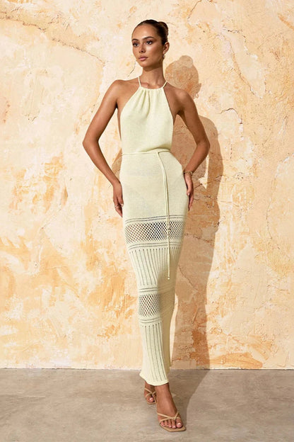 Woman wearing a light cream cover up dress against a textured beige wall
