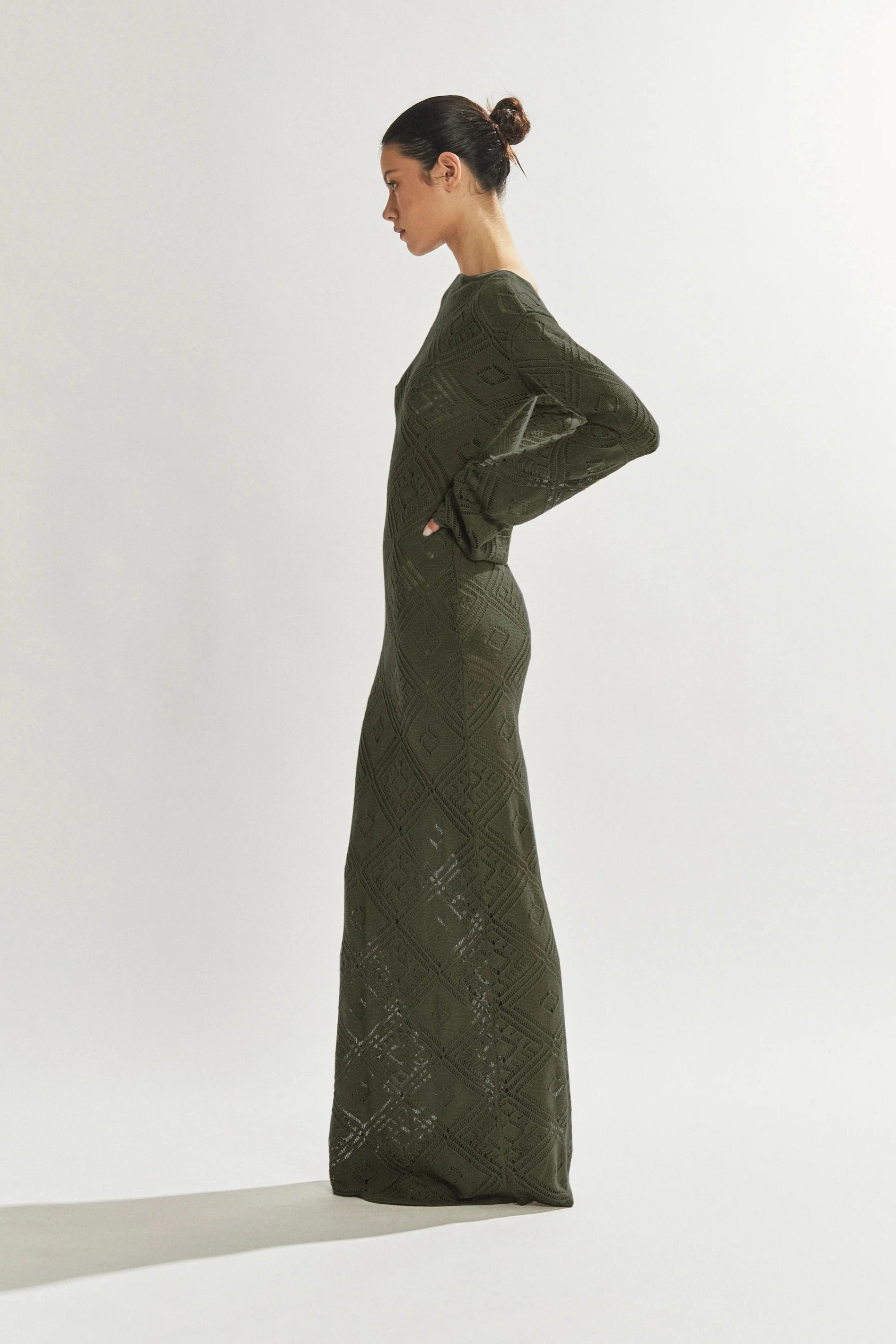 Woman wearing a long green cover up against a white background