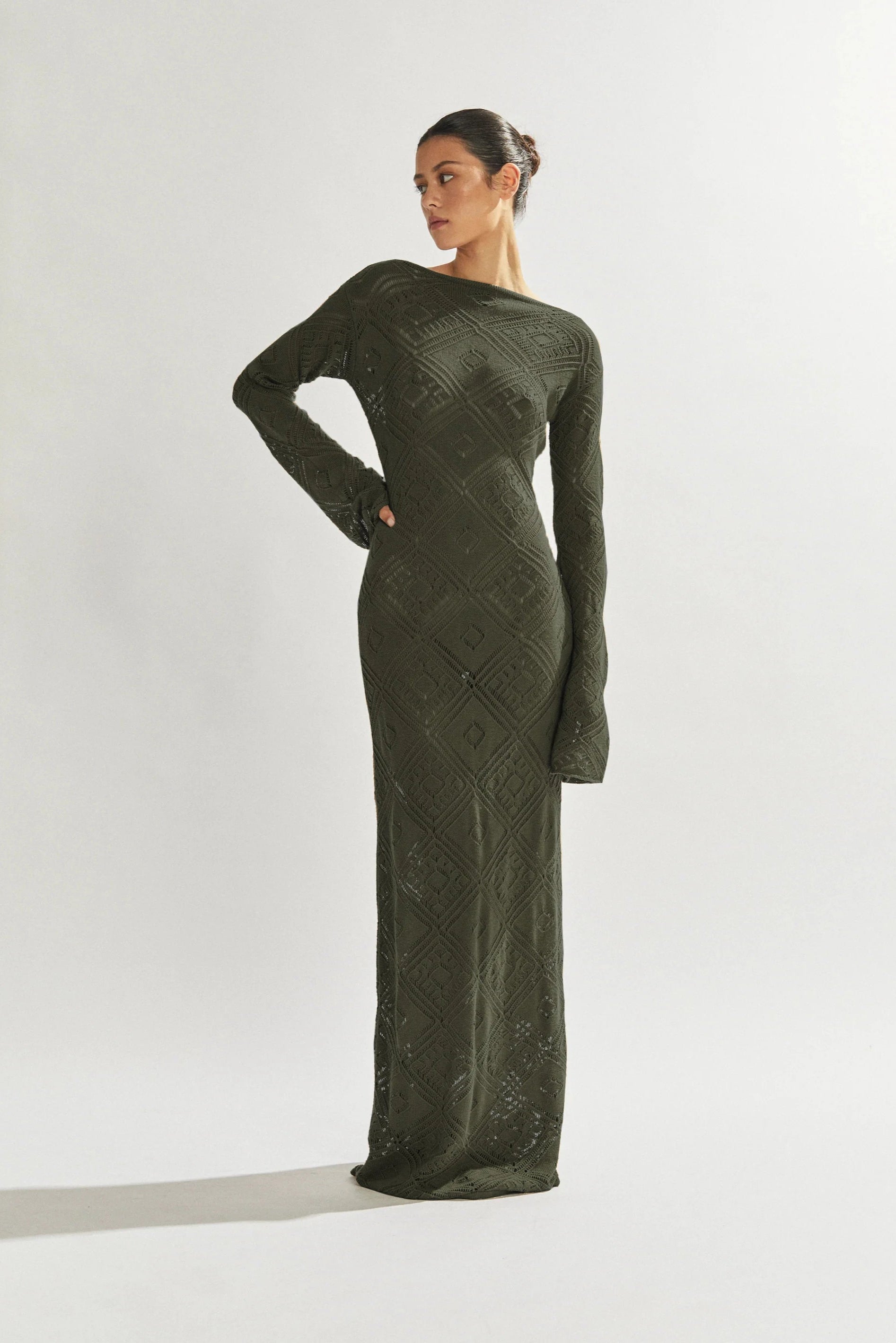 Woman wearing a long green cover up dress against a white background