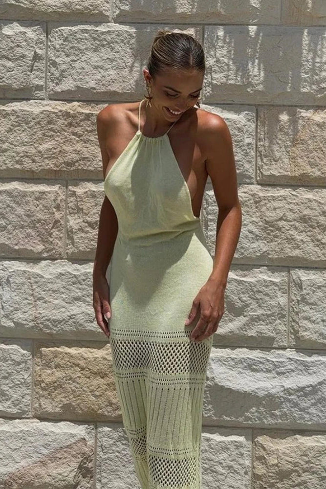 Woman wearing a off white dress standing against a stone wall.