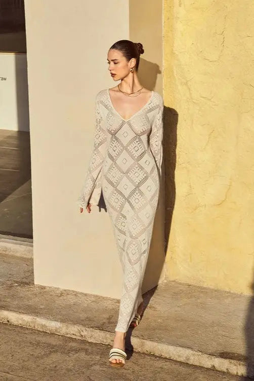 Woman wearing a patterned cover up standing against a beige wall.