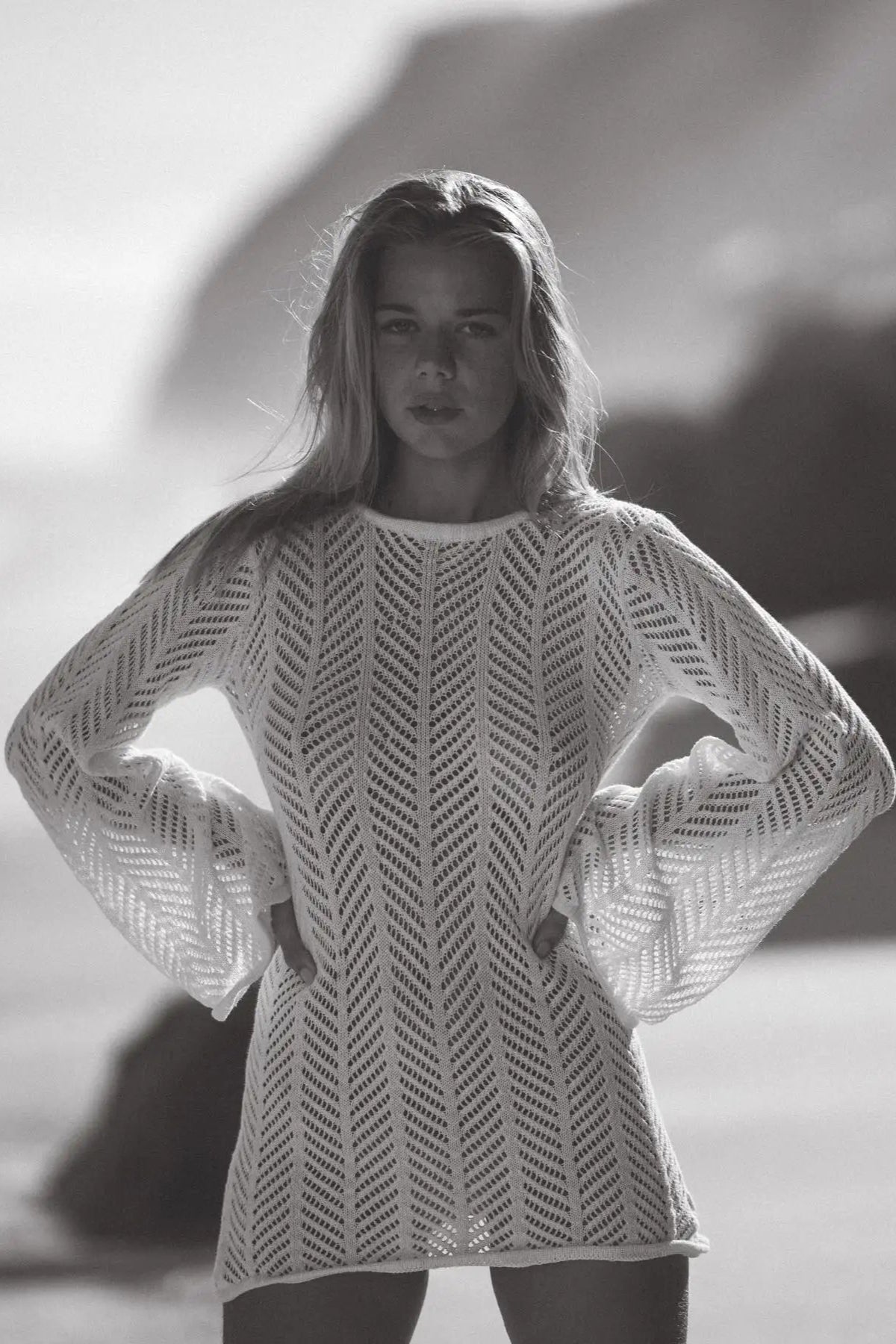 Woman wearing a patterned dress standing on a beach with a blurred background