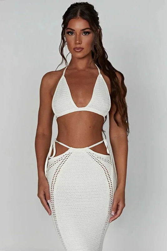 Woman wearing a white crochet dress against a plain background