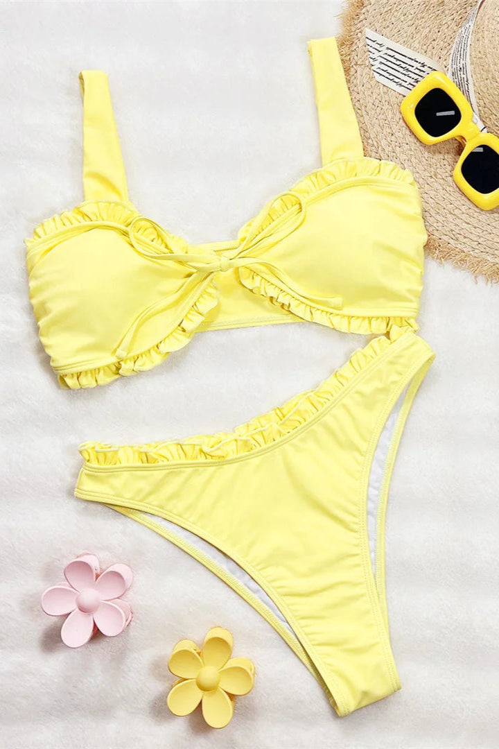 Yellow bikini set with a hat, sunglasses, and flowers on a white background