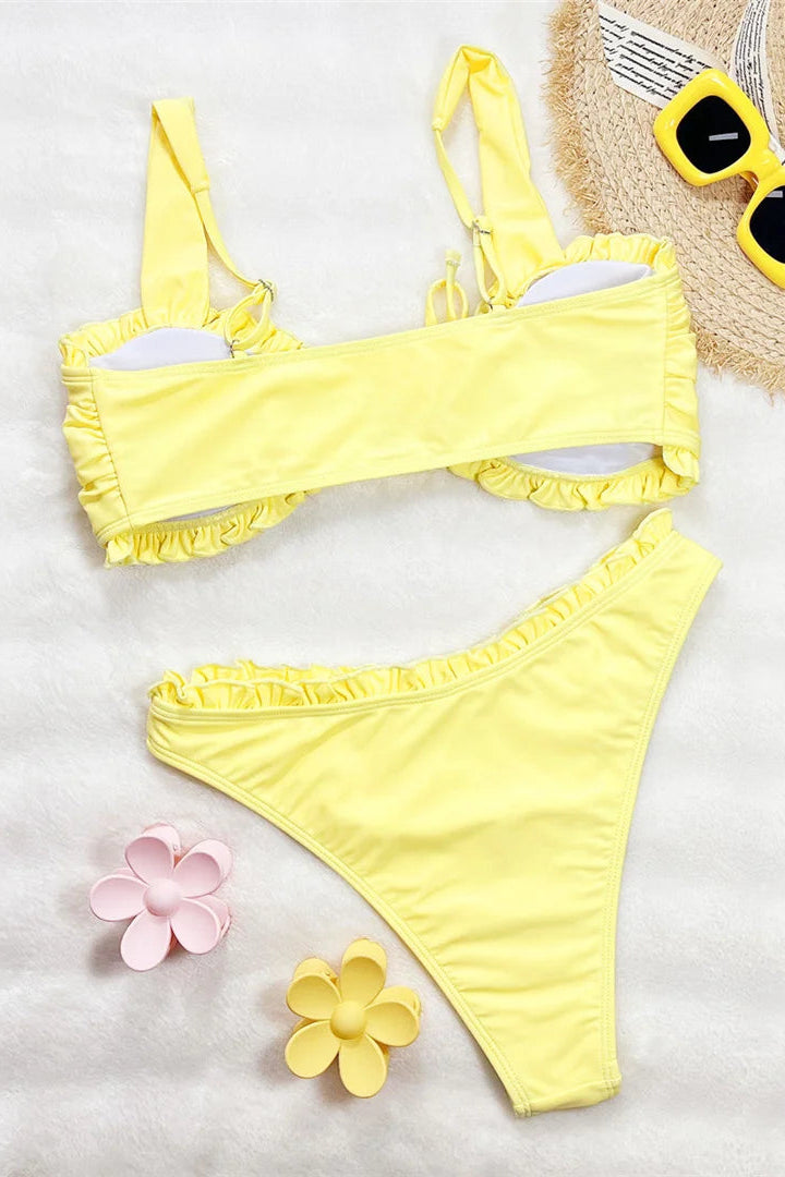 Yellow bikini set with sunglasses and flowers on a white background