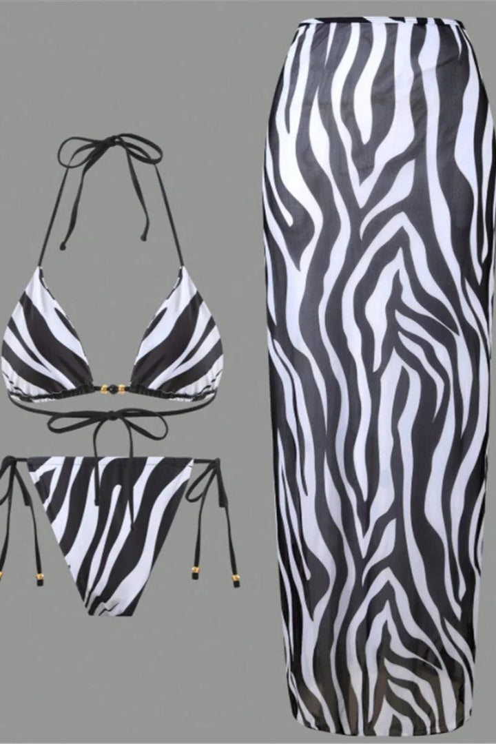 Zebra print bikini set with matching skirt cover up on a gray background